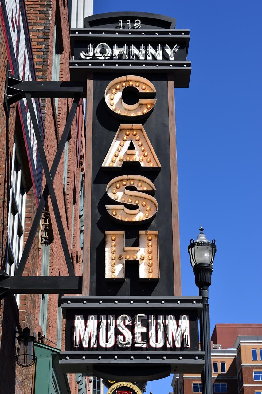 Vertical sign for Johnny Cash Museum mounted on building facade against clear blue sky