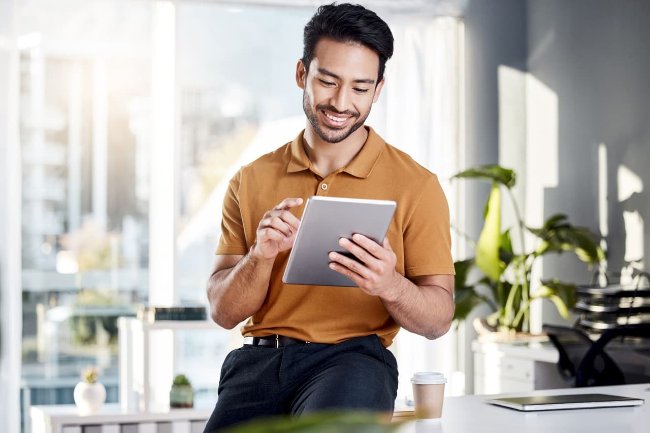 Smiling man using a tablet device with a blurred office background