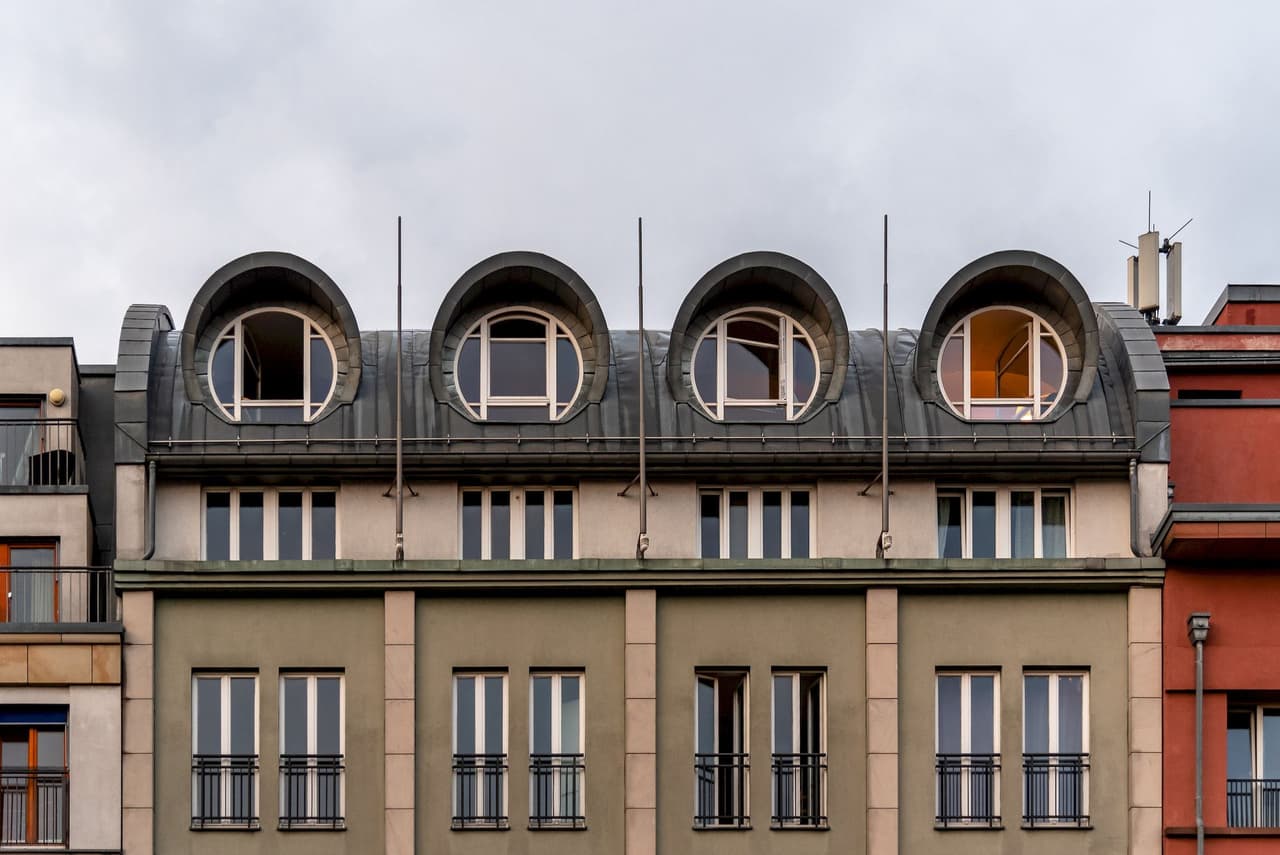 Modern building facade with five large round windows on the top floor under a cloudy sky