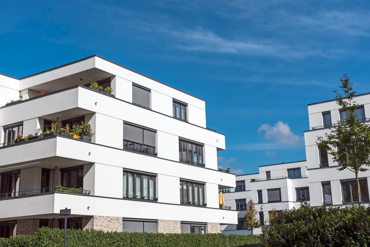 Modern white apartment buildings with balconies under a clear blue sky